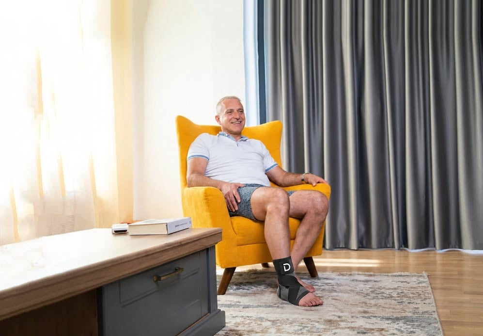 A man relaxing in a yellow armchair with the Dawnlit sleeve on his foot.