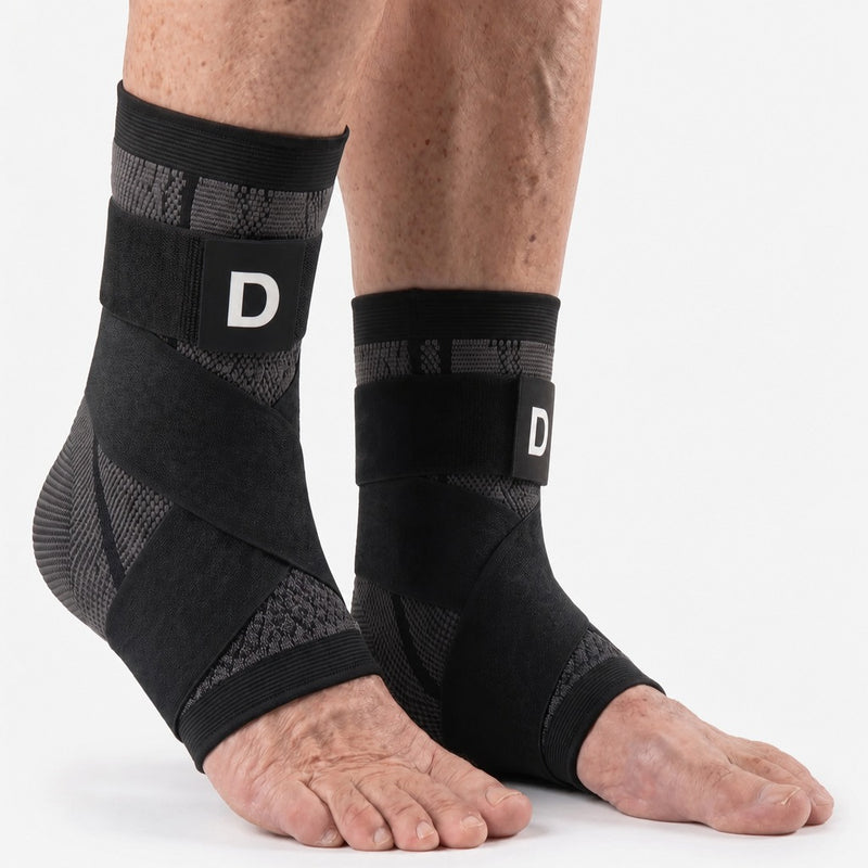Two feet wearing the black Dawnlit sleeve with its strap, seen from the front on a white background.